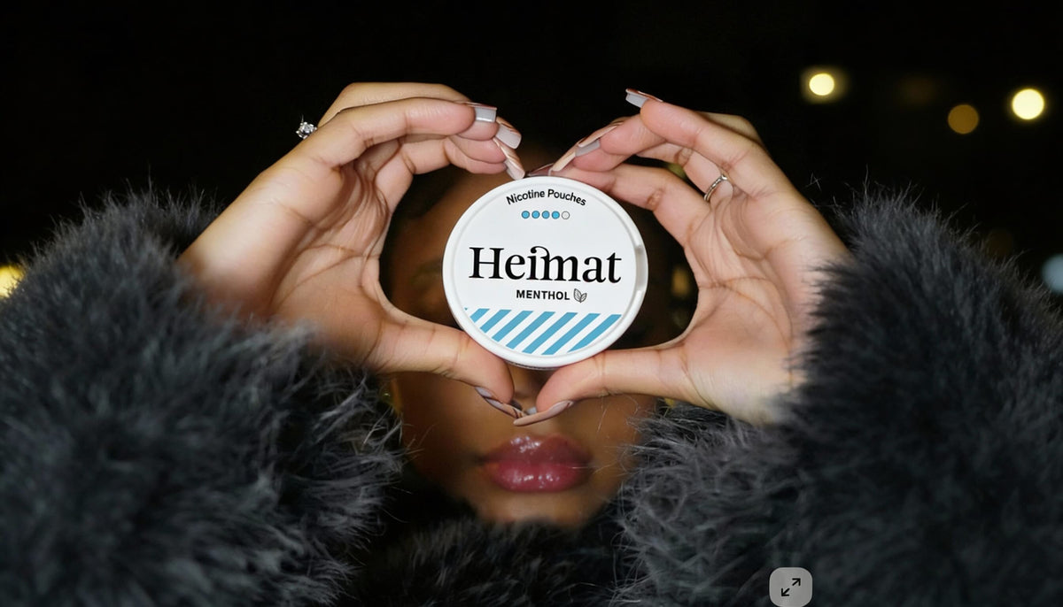 Heimat Menthol nicotine pouches can held in a heart-shaped hand gesture, lifestyle shot with a woman in a black coat